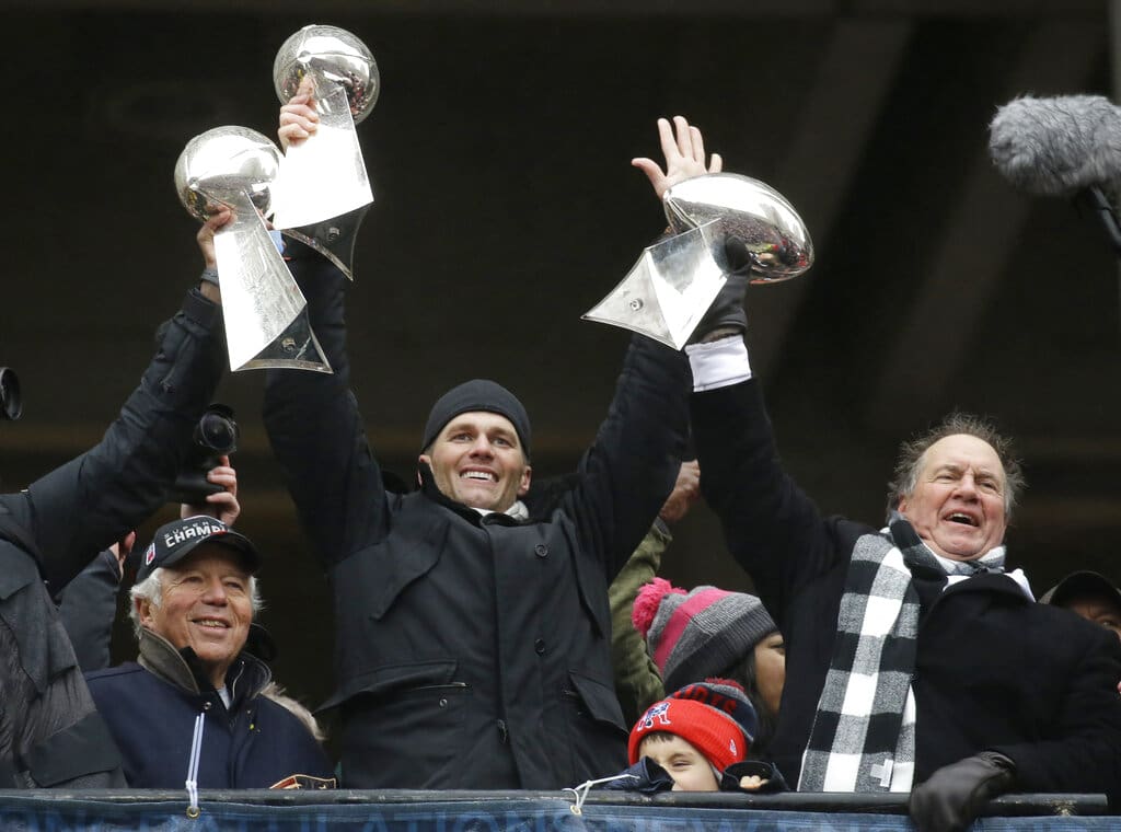 FILE - In this Feb. 7, 2017, file photo, New England Patriots quarterback Tom Brady holds up Super Bowl trophies along with head coach Bill Belichick, right, and team owner Robert Kraft, left, during a rally in Boston to celebrate the win over the Atlanta Falcons in the NFL Super Bowl 51 football game in Houston. Tom Brady is an NFL free agent for the first time in his career. The 42-year-old quarterback with six Super Bowl rings said Tuesday morning, March 17, 2020, that he is leaving the New England Patriots. The Patriots Dynasty won six Super Bowls. (AP Photo/Elise Amendola, File)